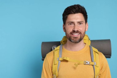 Açık mavi arka planda sırt çantalı mutlu adam, mesaj için yer var. Etkin turizm