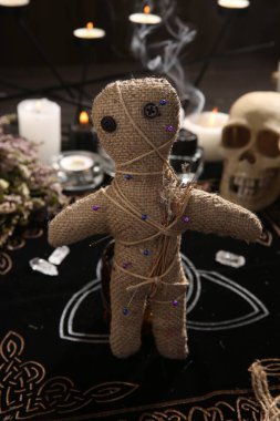 Voodoo bebeği, kapalı bir masa üzerinde iğne ve kurumuş çiçekler.