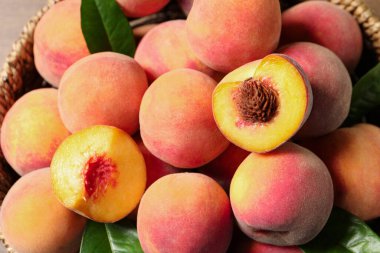 Masanın üstünde yeşil yapraklı taze şeftali dilimleri var.