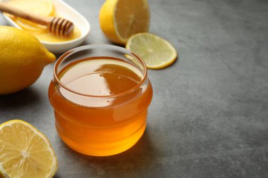 Tatlı bal ve taze limonlar gri masada, yakın plan. Metin için boşluk