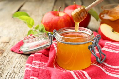 Dipper 'dan kavanoza tatlı bal damlatıyor ve tahta masada taze elmalar, seçici bir odak. Metin için boşluk