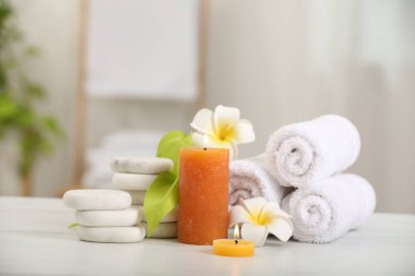 Beyaz mermer masa üzerinde farklı spa ürünleri ve plumeria çiçekleri içeren kompozisyon.