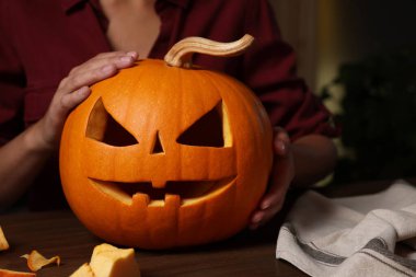 Ahşap masada oyulmuş balkabağı tutan kadın, yakın plan.