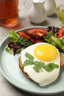 Lezzetli yumurta tabağı, açık gri masada bir dilim ekmek ve salata, yakın plan.