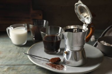 Moka demliğinde demlenmiş kahve ve kırsal ahşap masada cam.