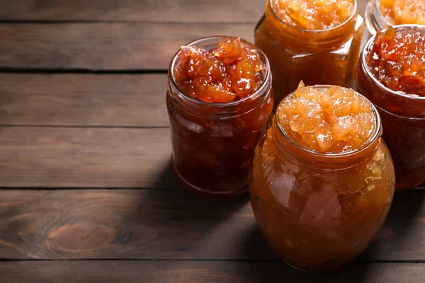 Delicious apple jam in jars on wooden table. Space for text