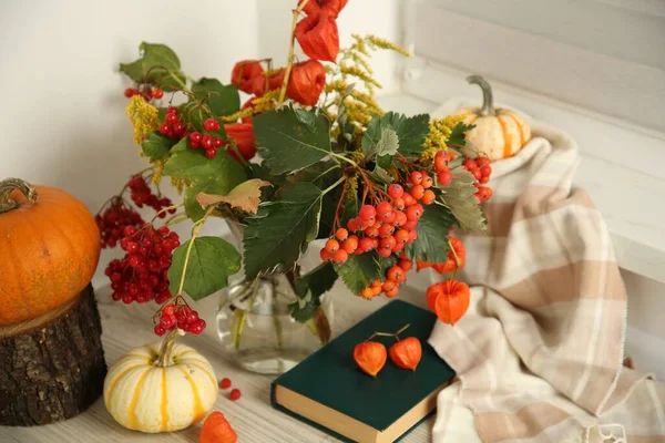 Beautiful autumn composition with different pumpkins and book indoors