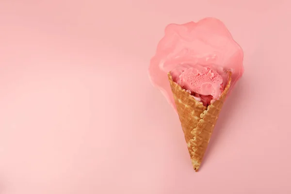 Melted ice cream in wafer cone on pink background, top view. Space for text