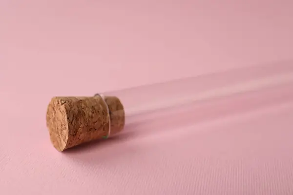 Test tube on pink background, closeup. Laboratory glassware