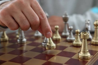 Satranç tahtasında satranç taşını hareket ettiren adam, yakın plan