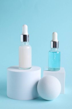 Açık mavi arkaplanda kozmetik serumunun şık sunumu