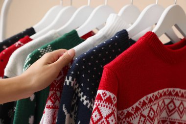 Kadın Noel süveterini askıdan seçiyor, yakın plan.