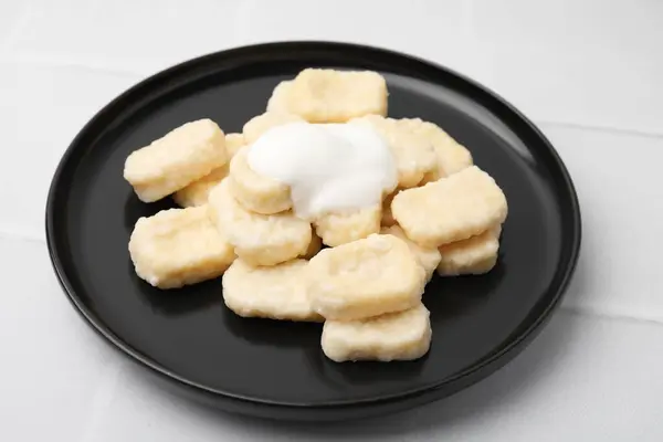 Plate of tasty lazy dumplings with sour cream on white tiled table