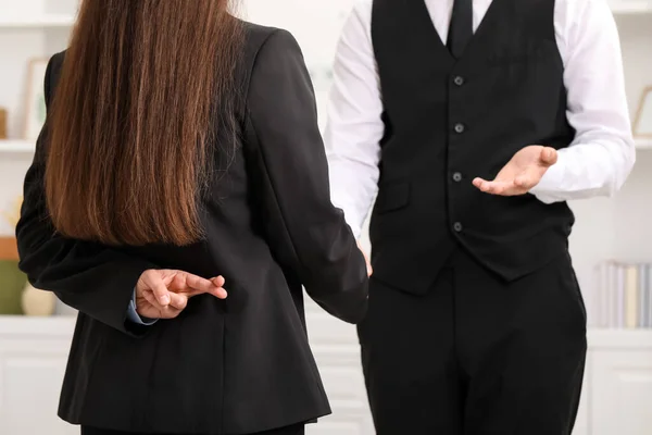 Businesswoman crossing fingers behind her back while meeting with colleague in office, closeup