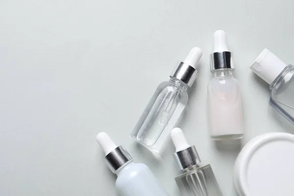 Molte Bottiglie Siero Cosmetico Sfondo Grigio Chiaro Posa Piatta Spazio — Foto Stock