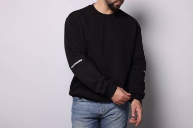 Beyaz arka planda şık süveterli bir adam, yakın plan.