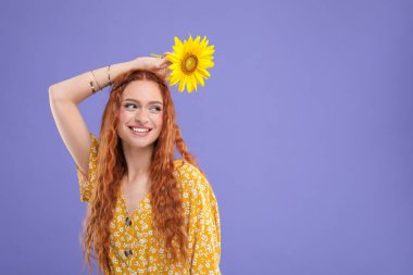 Menekşe arka planında ayçiçeği olan genç ve güzel bir hippi kadın.