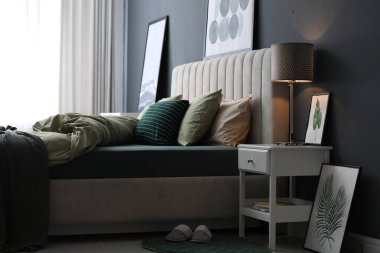 Modern oda içinde yeni şam fıstıklı çarşafları olan rahat bir yatak.