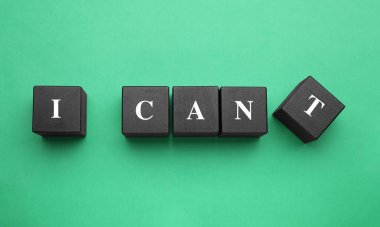 Motivasyon konsepti. I Can 'den I Can' e geçiş cümlesini yeşil arkaplandaki T harfli siyah tahta küpü kaldırarak yapabilirim.