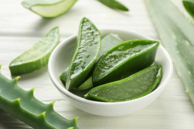 Taze aloe vera parçaları beyaz ahşap masada, yakın plan.