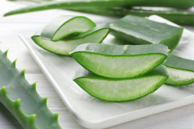 Taze aloe vera parçaları beyaz ahşap masada, yakın plan.