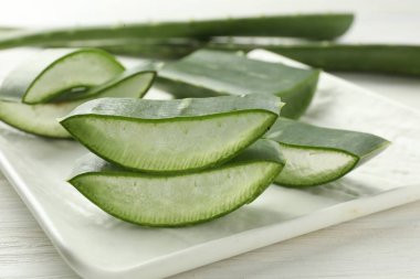 Taze aloe vera parçaları beyaz ahşap masada, yakın plan.