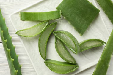 Taze aloe vera parçaları beyaz ahşap masa üzerinde, düz yatıyordu