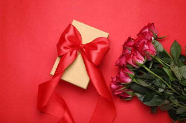 Kırmızı arka planda fiyonklu ve güllü güzel hediye kutusu, düz yatıyordu.