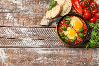 Lezzetli Shakshuka ahşap masada servis edilir, düz yatar. Metin için boşluk