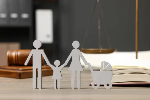 Family law. Figure of parents with children, book and gavel on wooden table
