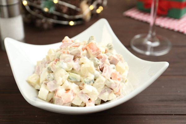 Традиционный русский салат Оливье подается на деревянном столе, крупным планом