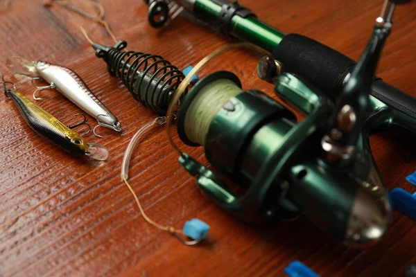 Fishing tackle. Reel, rod and lures on wooden table, closeup