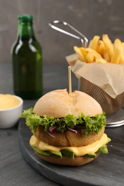 Tasty vegetarian burger served with french fries and beer on black table