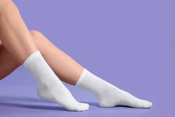 Woman in stylish white socks on violet background, closeup