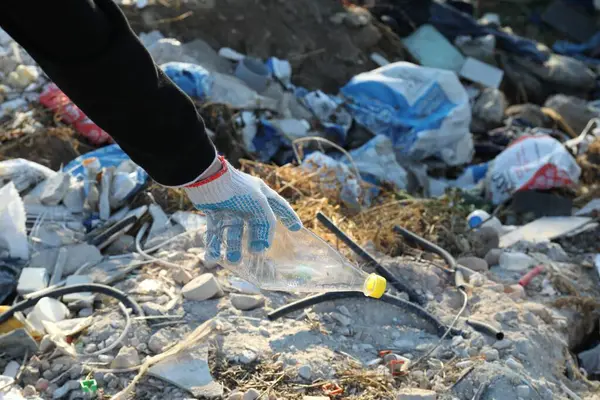 Woman picking up plastic garbage outdoors, closeup