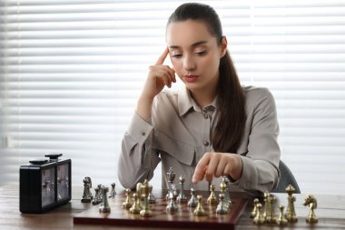 Woman playing chess during tournament at table indoors clipart