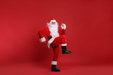 Mutlu noeller. Noel Baba kırmızı arka planda dans ediyor