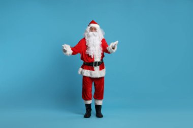 Mutlu noeller. Noel Baba açık mavi arka planda poz veriyor