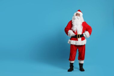 Mutlu noeller. Açık mavi arkaplanda poz veren Noel Baba, metin için boşluk