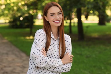 Parkta güzel gülüşü olan çekici genç bir kadının portresi. Çekici bayan kameraya poz veriyor.