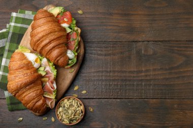 Somon, prosciutto ve ahşap masada kabak tohumlu lezzetli kruvasanlar. Metin için boşluk