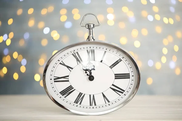 Clock showing five minutes until midnight on blurred background. New Year countdown
