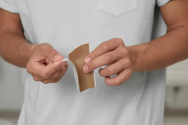 Man with sticking plaster indoors, closeup view