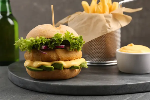 Tasty vegetarian burger with cutlet, cheese, avocado and onion on black table, closeup. Space for text