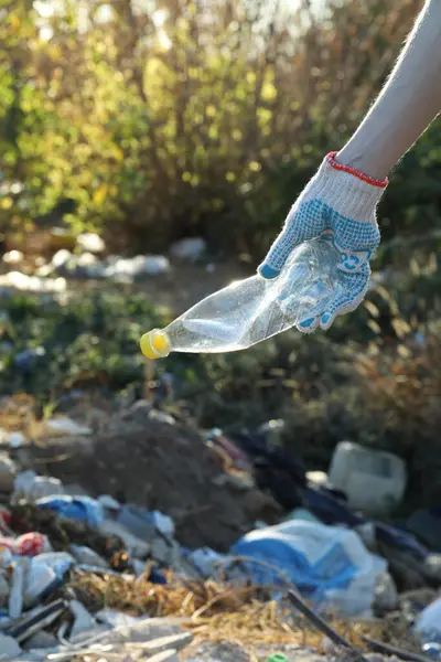 Woman picking up plastic garbage outdoors, closeup