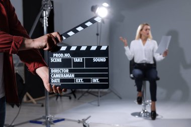 Oyuncu seçimi. Duygusal kadın performans sergilerken, ikinci yardım kamerası stüdyoda gri arka planda, seçici odak noktasında el çırpıyor.