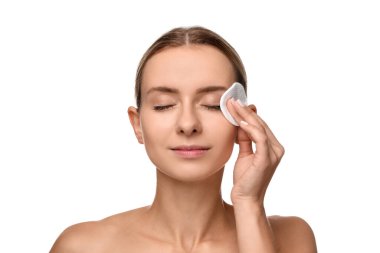 Güzel bir kadın beyaz arka planda pamuk yastıkla makyajı kaldırıyor.