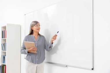 Profesör sınıfta beyaz tahtanın yanında ders veriyor, mesaj için yer var.