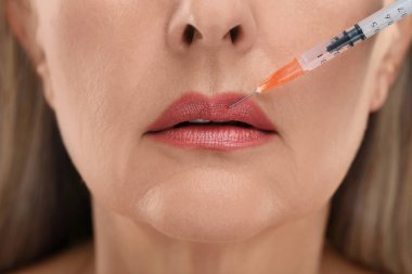Son sınıf öğrencisi kadın dudak iğnesi yaptırıyor, yakın plan. Estetik ameliyat