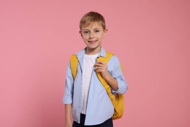 Pembe arka planda sırt çantası olan mutlu okul çocuğu.